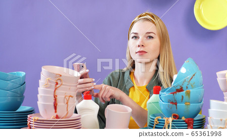 Attractive woman thought about how to wash a mountain, a pile of dirty dishes, an isolated background Attractive woman thought about how to wash a mountain, a pile of dirty dishes, an isolated background 65361998