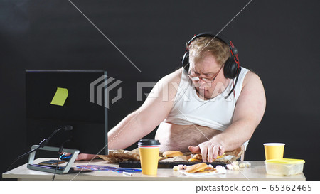 lazy, plump man in a t-shirt and headphones wanders the Web. People like computer games. The concept of addiction lazy, plump man in a t-shirt and headphones wanders the Web. People like computer games. The concept of addiction 65362465