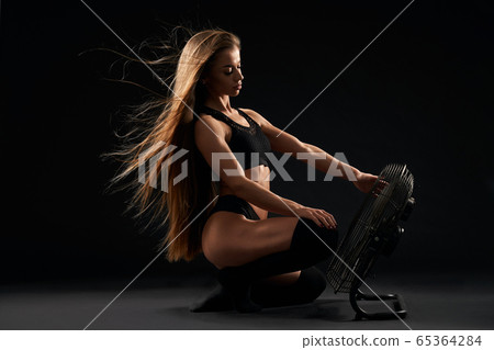 Sexy model with fan on studio floor. Sexy model with fan on studio floor. 65364284