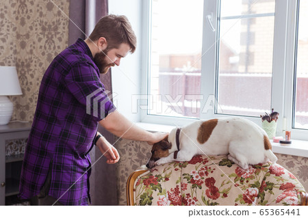 Close Up portrait handsome young hipster man plays and loves his good friend dog at home. Positive human emotions, facial expression, feelings. Close Up portrait handsome young hipster man plays and loves his good friend dog at home. Positive human emotions, facial expression, feelings. 65365441