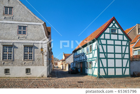 Typical fachwerk houses of old Klaipeda, Lithuania medieval town and cobbled pavement street. German style buildings of Middle Ages. Typical fachwerk houses of old Klaipeda, Lithuania medieval town and cobbled pavement street. German style buildings of Middle Ages. 65365796