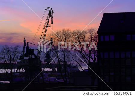 Silhouettes of port crane, trees and building in beautiful sunset in port harbor in Klaipeda, Lithuania. Silhouettes of port crane, trees and building in beautiful sunset in port harbor in Klaipeda, Lithuania. 65366061