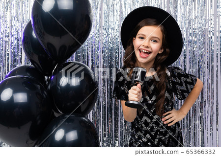 portrait of a young singer in a black dress with a microphone in her hands on a shiny background portrait of a young singer in a black dress with a microphone in her hands on a shiny background 65366332