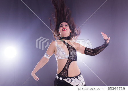 Young woman dancing in Tribal Fusion style. Belly dance on the stage. Young woman dancing in Tribal Fusion style. Belly dance on the stage. 65366719