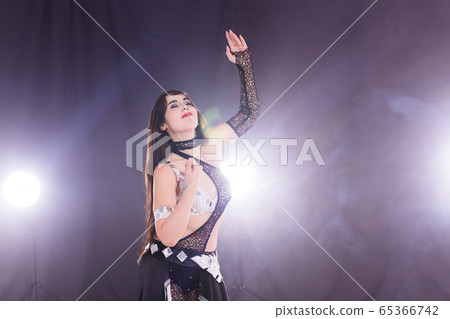 Spirituality dance. Beautiful sexy woman with luxury glossy eastern make-up dancing tribal fusion. Belly dance. Copy space. Spirituality dance. Beautiful sexy woman with luxury glossy eastern make-up dancing tribal fusion. Belly dance. Copy space. 65366742