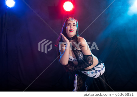 Young woman belly dancer in exotic dress with gold, dancing tribal fusion dance in studio. Young woman belly dancer in exotic dress with gold, dancing tribal fusion dance in studio. 65366851