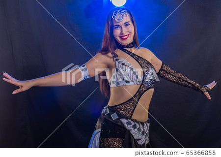 Young woman belly dancer in exotic dress with gold, dancing tribal fusion dance in studio. Young woman belly dancer in exotic dress with gold, dancing tribal fusion dance in studio. 65366858