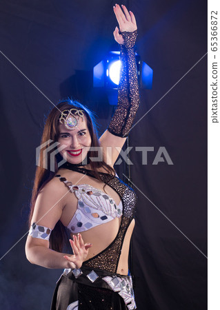 Young woman belly dancer in exotic dress with gold, dancing tribal fusion dance in studio. 65366872
