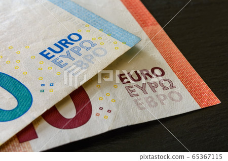 Macrophotography of word euro on two euro banknotes over a black background. 65367115