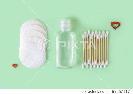 Cleansing lotion or tonic in a transparent jar, cotton pads and cotton buds on a pastel mint Cleansing lotion or tonic in a transparent jar, cotton pads and cotton buds on a pastel mint 65367117