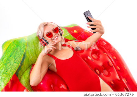 sexy blonde girl in a red swimsuit and sunglasses sitting on a swimming mattress and listening to sexy blonde girl in a red swimsuit and sunglasses sitting on a swimming mattress and listening to 65367279