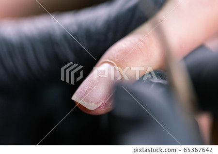 Process manicure close-up. Preparation for hardware manicure. Beautician in rubber gloves cuts the cuticle and processes nails. Process manicure close-up. Preparation for hardware manicure. Beautician in rubber gloves cuts the cuticle and processes nails. 65367642