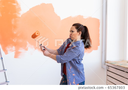 Dancing funny woman painting interior wall of new house. Redecoration, renovation, apartment repair and refreshment concept. Dancing funny woman painting interior wall of new house. Redecoration, renovation, apartment repair and refreshment concept. 65367803