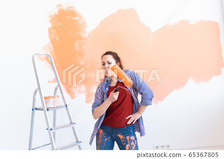 Dancing funny smiling woman painting interior wall of new house. Redecoration, renovation, apartment repair and refreshment concept. Dancing funny smiling woman painting interior wall of new house. Redecoration, renovation, apartment repair and refreshment concept. 65367805