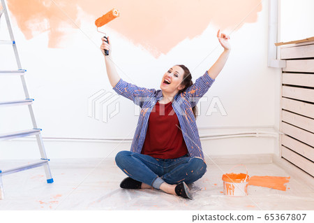 Happy smiling woman painting interior wall of new house. Redecoration, renovation, apartment repair and refreshment concept. Happy smiling woman painting interior wall of new house. Redecoration, renovation, apartment repair and refreshment concept. 65367807