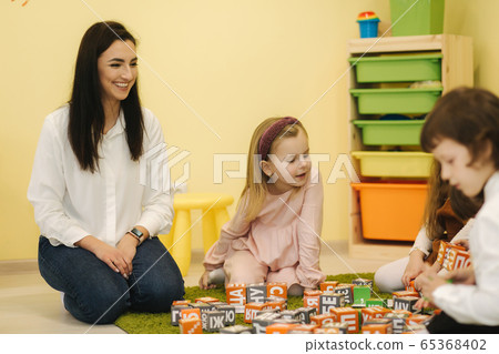 Childres sits with techers on the floor and learning. Preschool 65368402