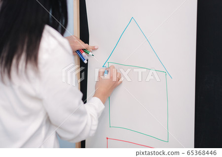 Teacher writes on blackboard. Female draws a house. Preschool Teacher writes on blackboard. Female draws a house. Preschool 65368446