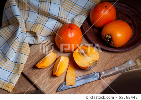 Whole ripe persimmon and sliced fruit on a wooden Whole ripe persimmon and sliced fruit on a wooden 65368448