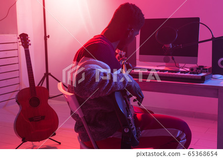 Create music and a recording studio concept - Black man guitarist recording electric bass guitar track in home studio 65368654