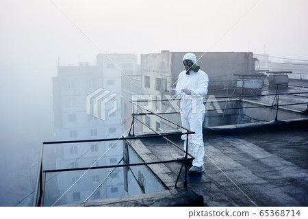 Worker scientist wearing protective coverall and gas mask doing ecological tests on the roof Worker scientist wearing protective coverall and gas mask doing ecological tests on the roof 65368714