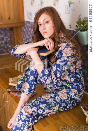 Young red-haired woman relaxing at home reading book. Quarantine, isolation, coronavirus pandemic world. Stay at home. Young red-haired woman relaxing at home reading book. Quarantine, isolation, coronavirus pandemic world. Stay at home. 65368997