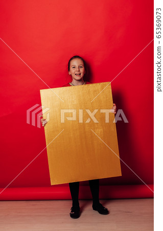 Schoolgirl's girl holds sign for inscriptions on red background Schoolgirl's girl holds sign for inscriptions on red background 65369073