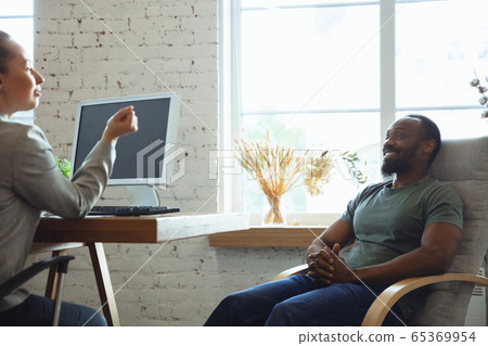 Young man sitting in office during the job interview with female employee, boss or HR-manager, talking, thinking, looks confident Young man sitting in office during the job interview with female employee, boss or HR-manager, talking, thinking, looks confident 65369954