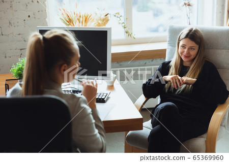 Young woman sitting in office during the job interview with female employee, boss or HR-manager, talking, thinking, looks confident 65369960