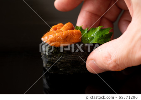 Itamae holding sea urchin sushi 65371296