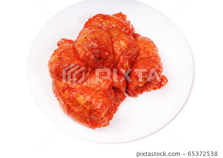 Uncooked marinated chicken thigh. Chicken legs in a red marinade on a white plate .Isolated 65372538