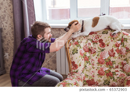 Happy young man sitting with his dog at home. Pet owner, animals and friendship concept. 65372903