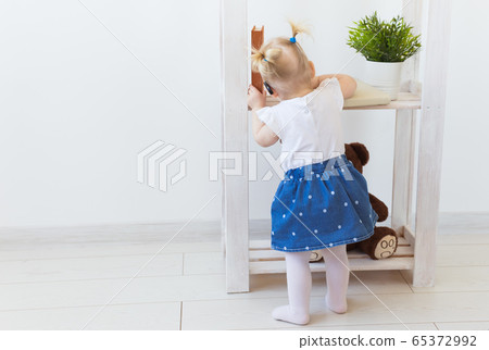 Hearing aid in baby girl's ear. Toddler child wearing a hearing aid at home. Disabled child, disability and deafness concept. Hearing aid in baby girl's ear. Toddler child wearing a hearing aid at home. Disabled child, disability and deafness concept. 65372992