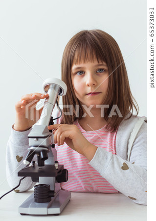 Child girl in science class using digital microscope. Technologies, children and learning concept. Child girl in science class using digital microscope. Technologies, children and learning concept. 65373031