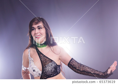 Young woman belly dancer in exotic dress with gold, dancing tribal fusion dance in studio. Young woman belly dancer in exotic dress with gold, dancing tribal fusion dance in studio. 65373619