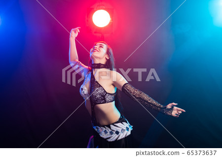 Young woman belly dancer in exotic dress with gold, dancing tribal fusion dance in studio. Young woman belly dancer in exotic dress with gold, dancing tribal fusion dance in studio. 65373637