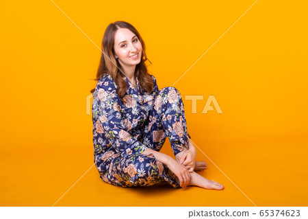 Excited young woman in home wear, widely smiling having fun. Isolated on yellow background. 65374623