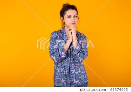 Excited young woman in blue home wear, widely smiling having fun. Isolated on yellow background. Excited young woman in blue home wear, widely smiling having fun. Isolated on yellow background. 65374625