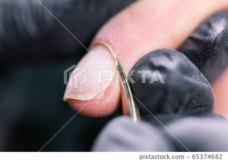 Manicurist use electric nail file drill in beauty salon. Perfect nails manicure process close up with burst flying debris. 65374682