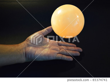 Crystal ball floating over hand On a black gray background Crystal ball floating over hand On a black gray background 65374741