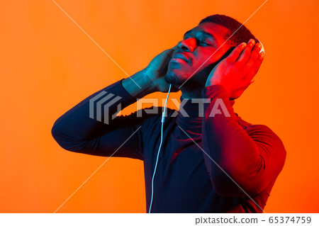 Neon portrait of handsome african american man in headphones. Listening to music. 65374759