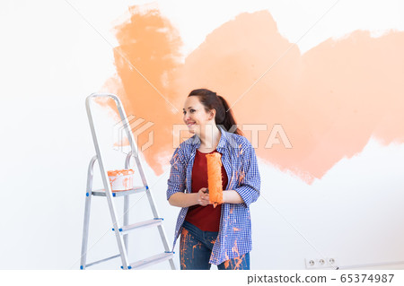Pretty young woman with painting roller indoors. Redecoration, renovation, apartment repair and refreshment concept. Pretty young woman with painting roller indoors. Redecoration, renovation, apartment repair and refreshment concept. 65374987