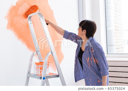 Renovation, redecoration and repair concept - middle-aged woman painting wall in new home. 65375024