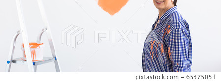 Close up middle-aged woman painting interior wall of home. Renovation, repair and redecoration concept. Close up middle-aged woman painting interior wall of home. Renovation, repair and redecoration concept. 65375051