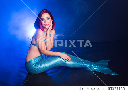 Mermaid with red hair resting on blue background. Fantasy concept. Mermaid with red hair resting on blue background. Fantasy concept. 65375123
