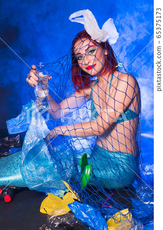 Fantasy stupid mermaid in deep ocean. Plastic trash and bottles pollution in ocean. Ecocatastrophe, garbage and plastic recycling concept. 65375173