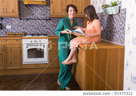 Charming mother is showing images in a book to her cute little daughter at home 65375322