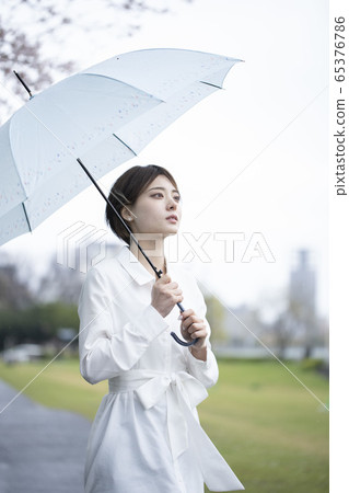 一件白色禮服的一個少婦走與一把傘的在雨中 一件白色禮服的一個少婦走與一把傘的在雨中 65376786