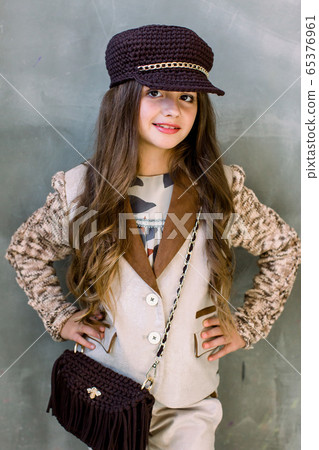Beautiful little girl. Portrait. Studio shot of little girl in a light suit, a golden sneakers and a hat 65376961