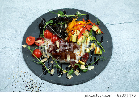 Hawaiian salmon fish poke bowl with rice, radish,cucumber, tomato, sesame seeds and seaweeds. Buddha bowl. Diet food Hawaiian salmon fish poke bowl with rice, radish,cucumber, tomato, sesame seeds and seaweeds. Buddha bowl. Diet food 65377479