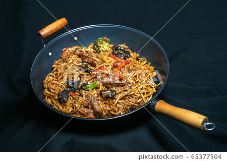 Udon stir-fry noodles with shrimp and vegetables in wok pan on black burned wooden background 65377504